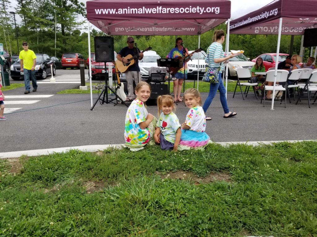 children in tie dye shirts listen to live music at Woofstock Festival
