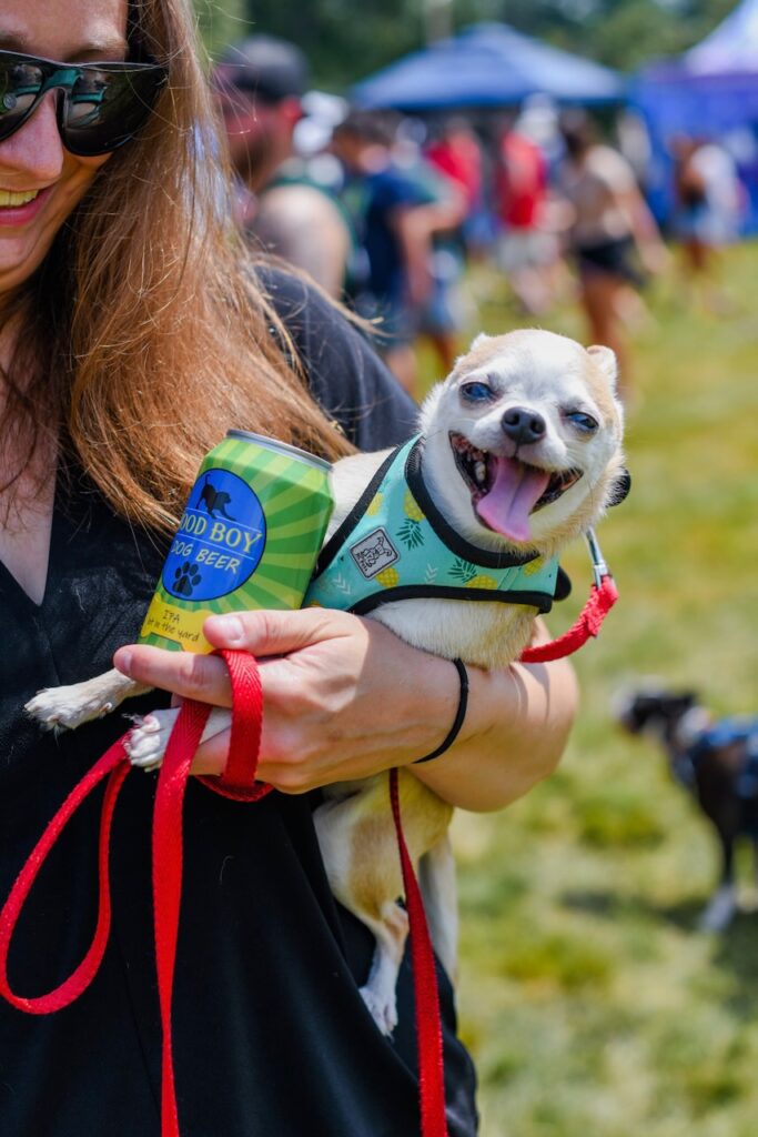 woman holds a small smiling dog at Woofstock Festival