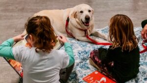 children quietly read a story to a yellow lab