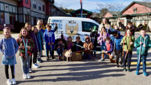 A class of elementary students stand in front of the AWS van with a donation of homemade dog leashes.