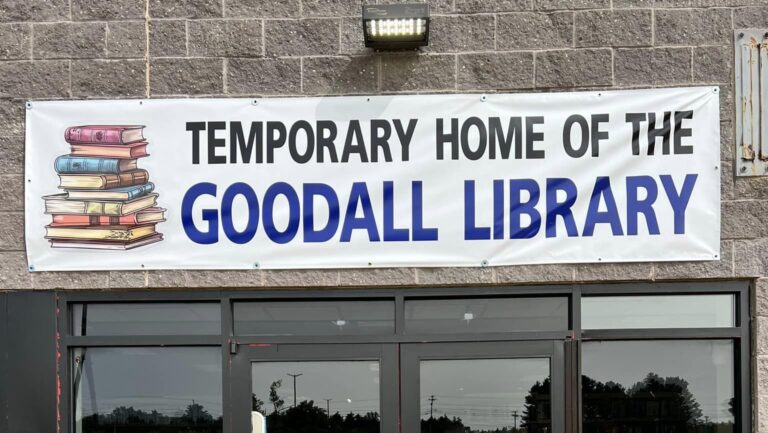 A large sign for Goodall Library hanging over the front door of a building.