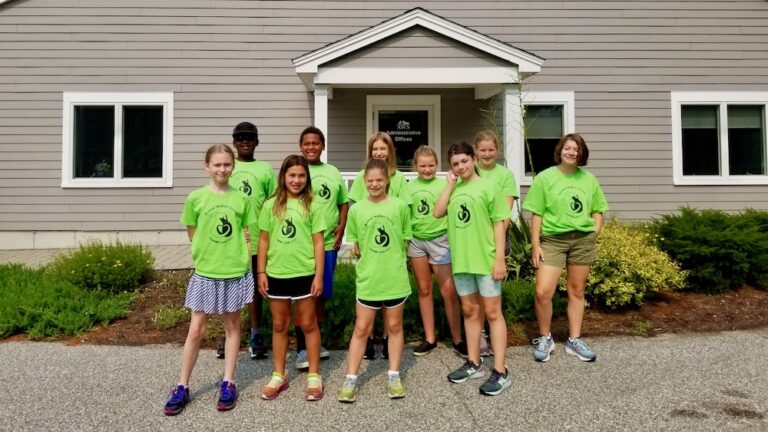 A group of children pose in front of the AWS building during Summer Camp.