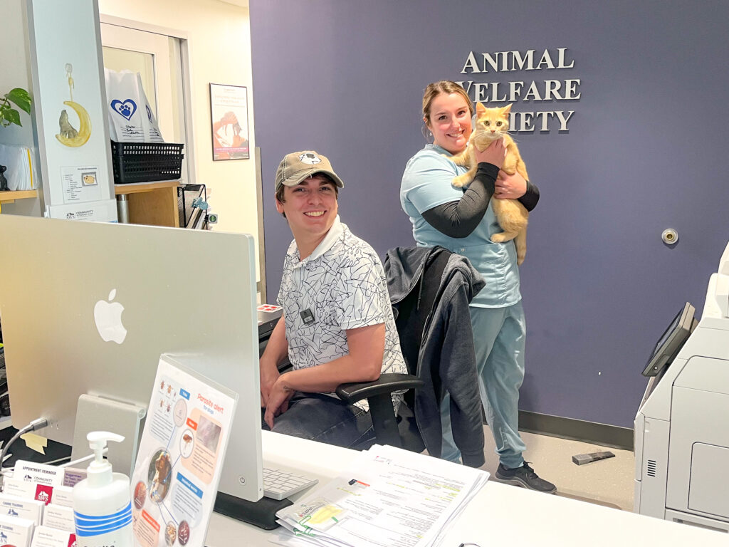 client service representative and veterinary technician holding an orange cat in aws lobby