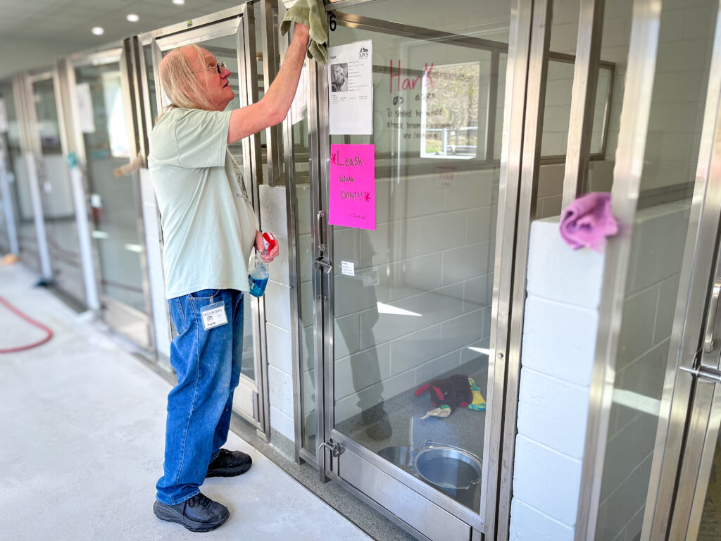 An AWS Adoption Center volunteer cleans dog kennels.