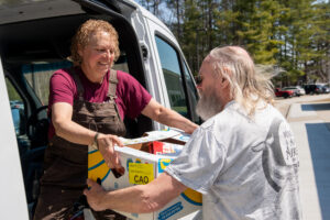 Jenn Banks, an AWS staff member unloads a pet food bank delivery with help from a volunteer.