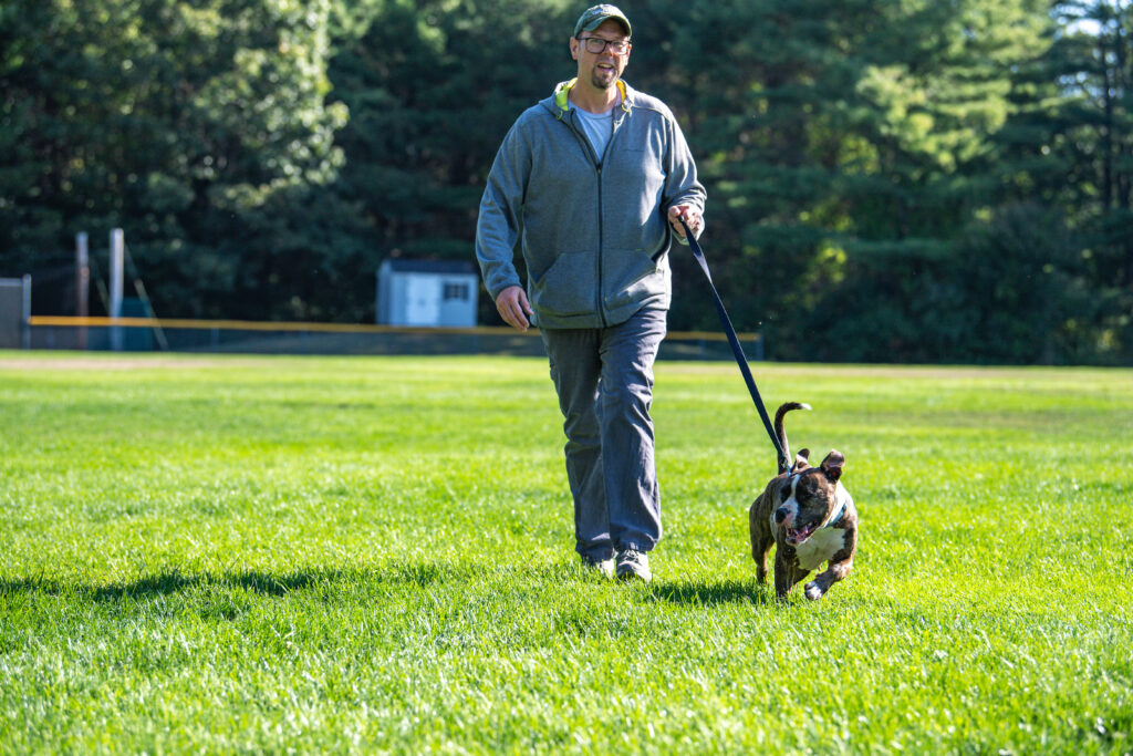 Daisy doing one of her favorite things, walking, with an AWS volunteer outside.