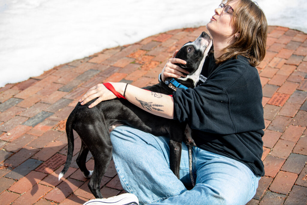 Glimmer the dog, who's looking for Glimmer's Lucky Match, snuggles up with an ACT and licks their face.